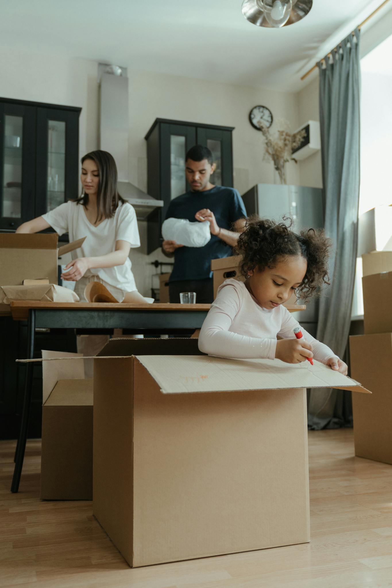 A family of three unpacking boxes in their new home, capturing the moving process.