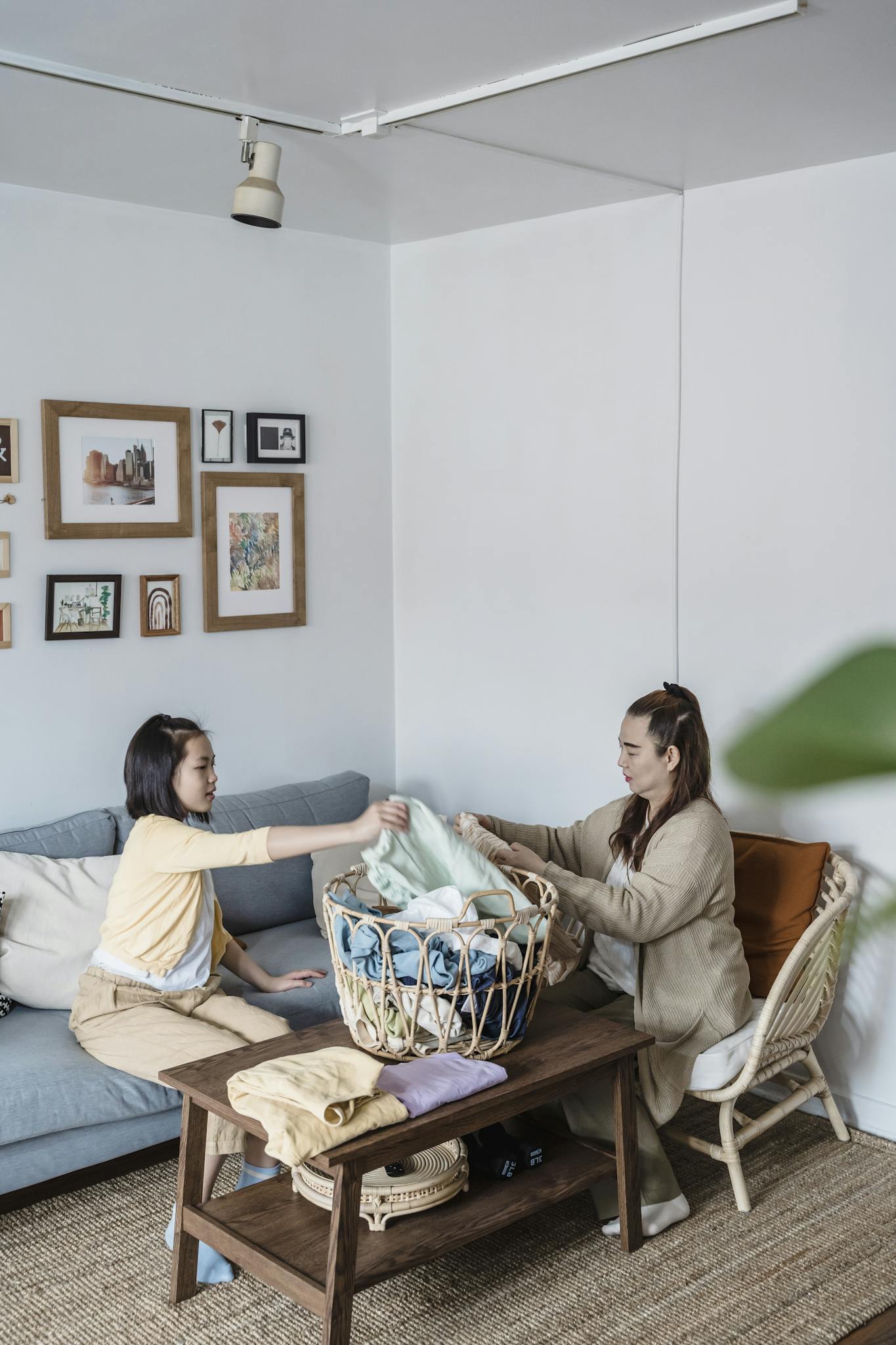 Mother and daughter folding laundry together in a cozy living room setting.